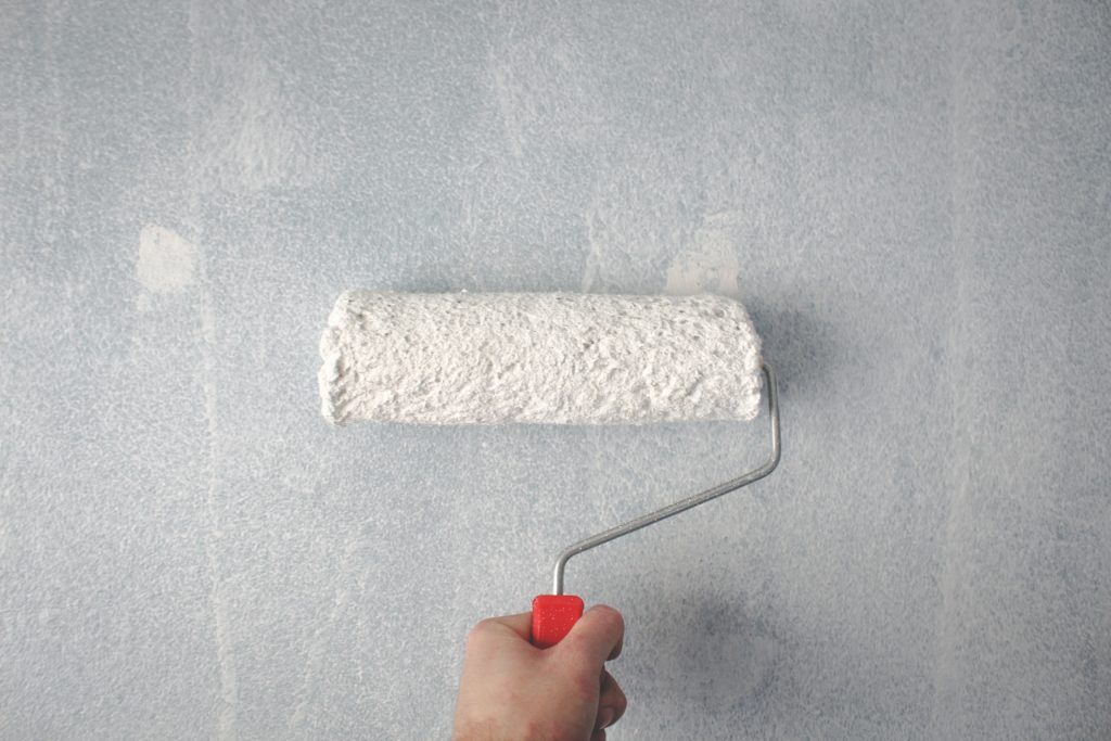 A person using a paint roller on a wall